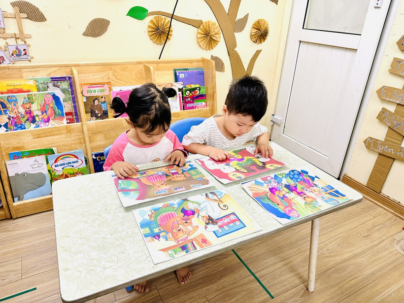 A couple of children sitting at a table with booksDescription automatically generated