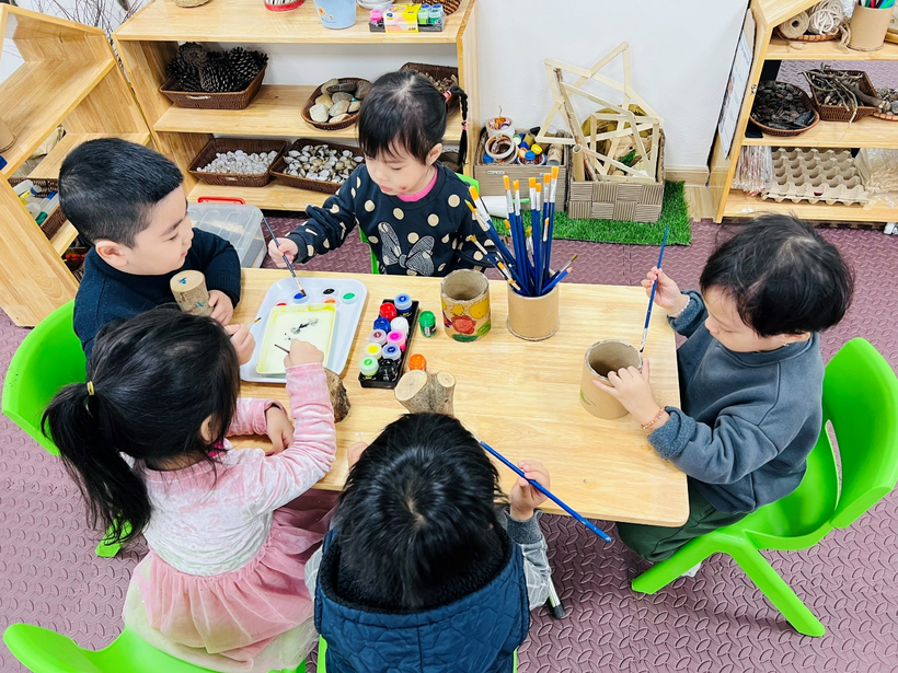 A group of children sitting at a table painting

Description automatically generated